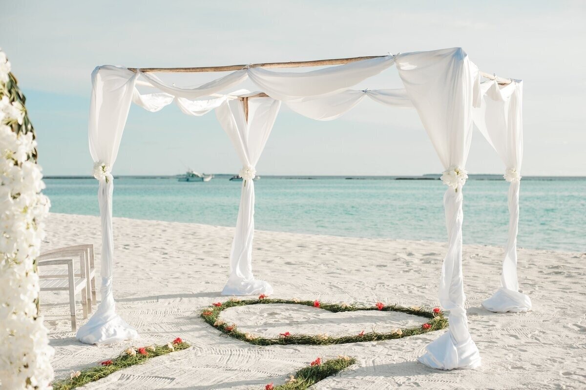 Destination wedding ceremony overlooking a sandy beach and blue ocean.